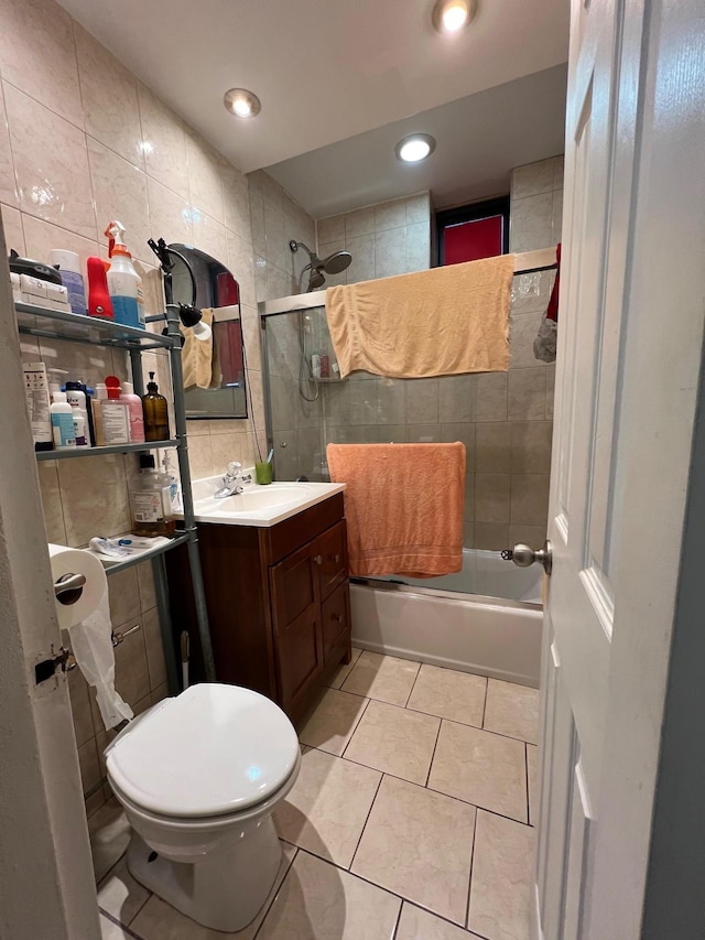 full bathroom with bath / shower combo with glass door, tasteful backsplash, tile walls, vanity, and tile patterned floors