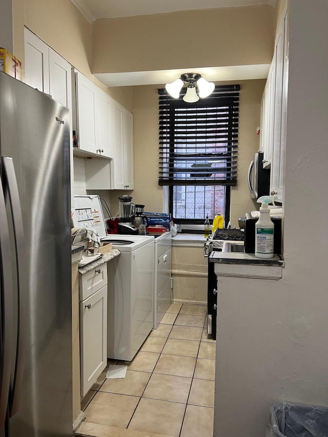 kitchen with light tile patterned floors, appliances with stainless steel finishes, white cabinetry, washing machine and dryer, and a chandelier