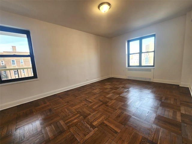 empty room featuring radiator and dark parquet floors