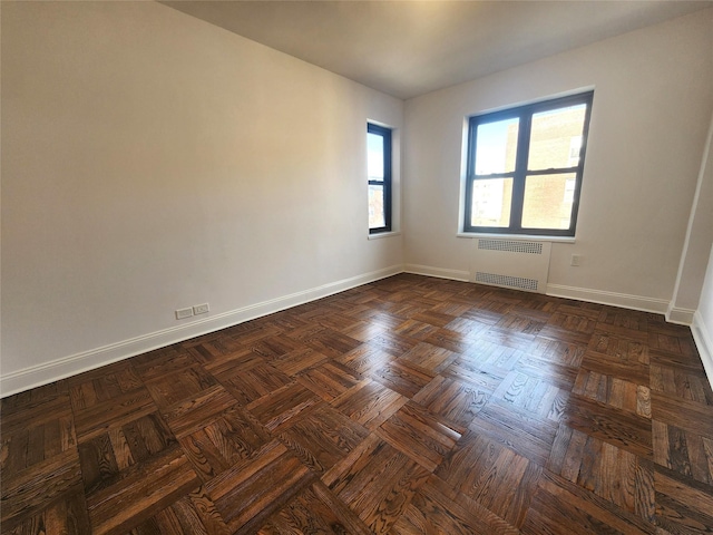 empty room featuring radiator and dark parquet floors