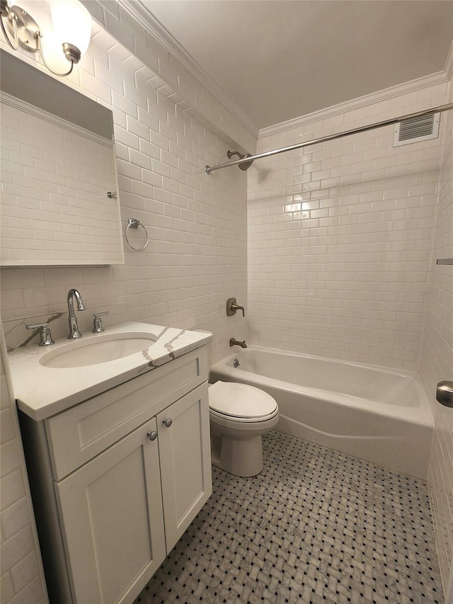 full bathroom featuring toilet, tiled shower / bath, tile walls, ornamental molding, and vanity