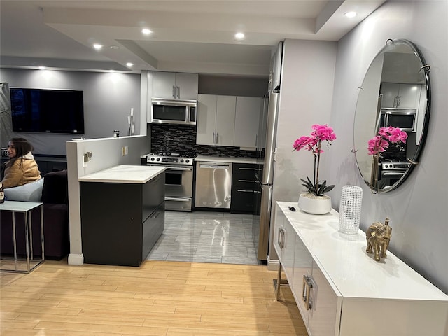 kitchen with appliances with stainless steel finishes, gray cabinetry, light hardwood / wood-style flooring, and decorative backsplash