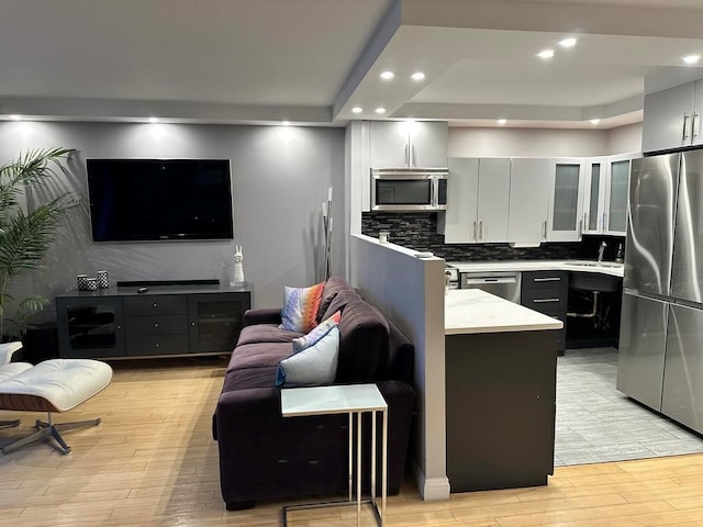 kitchen with sink, white cabinetry, light hardwood / wood-style flooring, a kitchen island, and stainless steel appliances