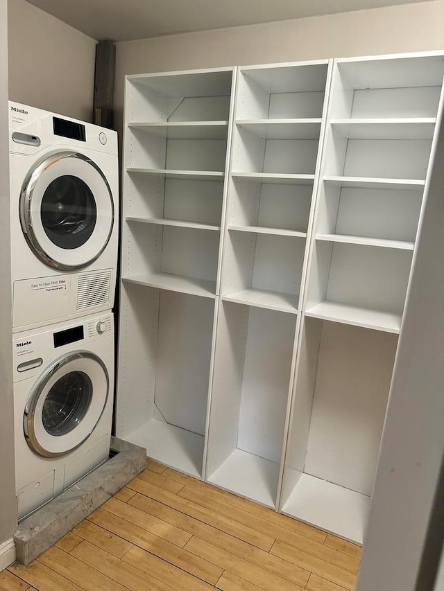 laundry room with stacked washer and dryer and light wood-type flooring