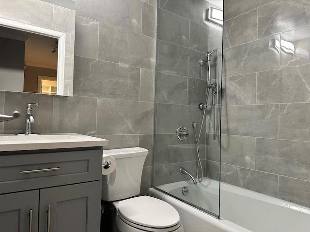 full bathroom with toilet, tile walls, vanity, tiled shower / bath combo, and decorative backsplash