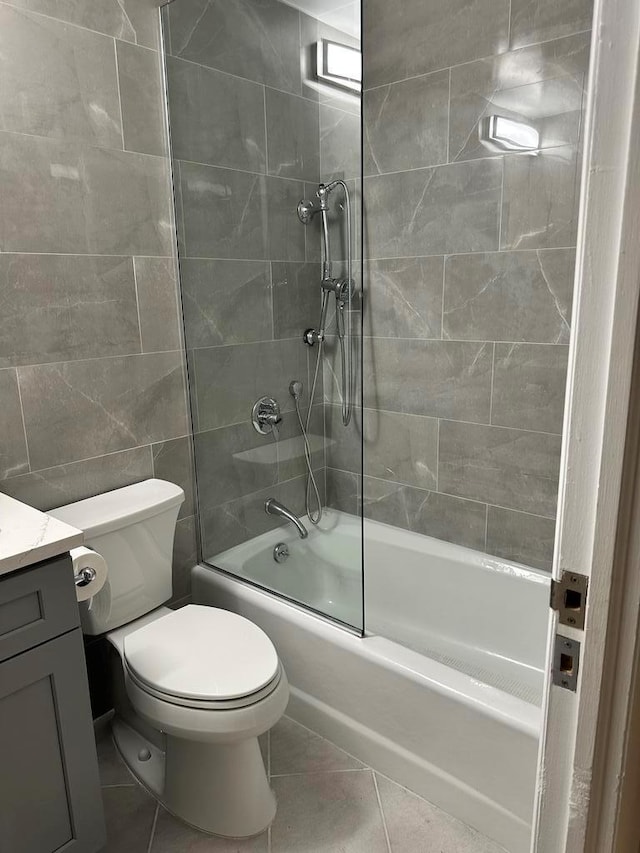 full bathroom featuring tile walls, tile patterned flooring, vanity, tiled shower / bath combo, and toilet