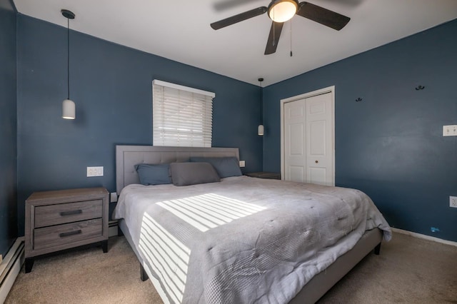 carpeted bedroom with a baseboard heating unit, a closet, and ceiling fan