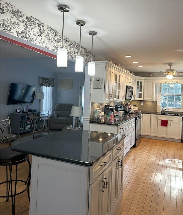 kitchen with tasteful backsplash, appliances with stainless steel finishes, a kitchen island, light hardwood / wood-style floors, and white cabinets