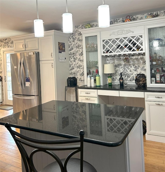 kitchen featuring pendant lighting, stainless steel fridge, dark stone countertops, and light wood-type flooring