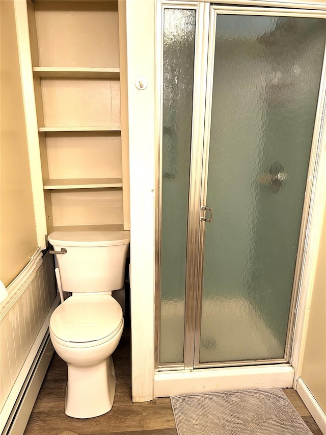 bathroom with toilet, a shower with door, hardwood / wood-style floors, and a baseboard heating unit