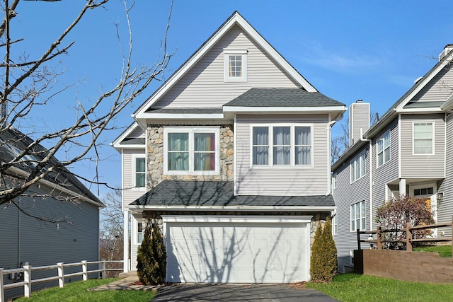 view of front of property with an attached garage, fence, stone siding, and driveway