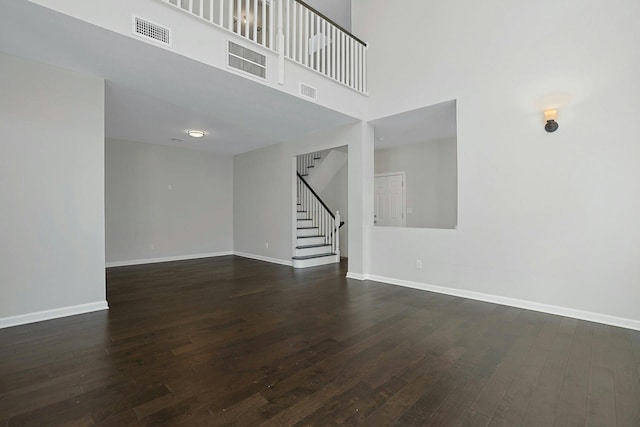 spare room with stairs, visible vents, baseboards, and dark wood-style flooring