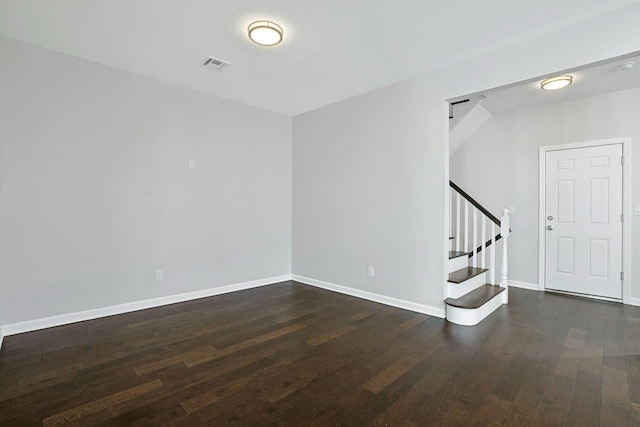 spare room featuring stairway, wood finished floors, visible vents, and baseboards