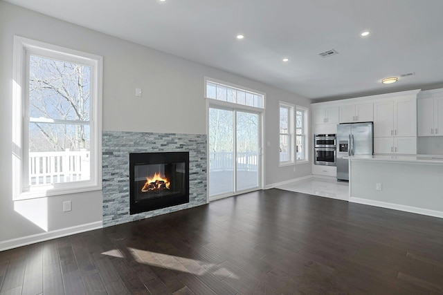 unfurnished living room featuring wood finished floors, visible vents, baseboards, a fireplace, and recessed lighting