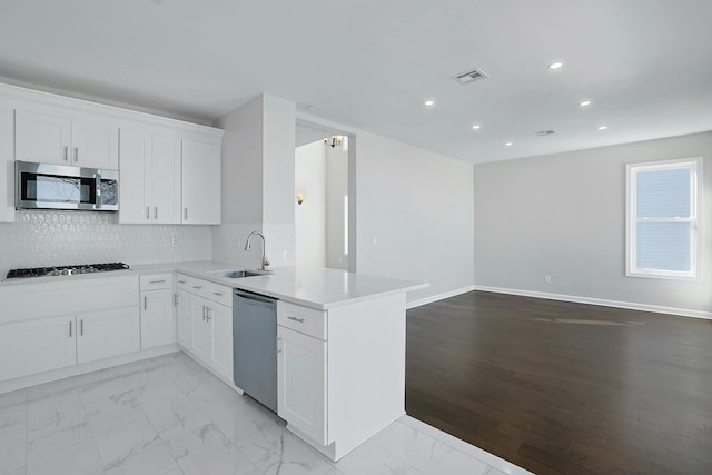 kitchen with light countertops, decorative backsplash, appliances with stainless steel finishes, marble finish floor, and a sink