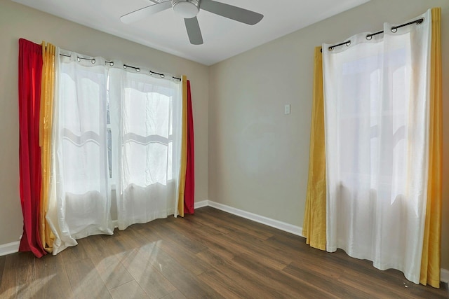 spare room featuring ceiling fan, baseboards, and dark wood-style flooring