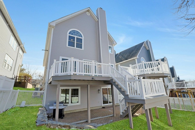 back of property featuring a fenced backyard, a lawn, a deck, and a chimney