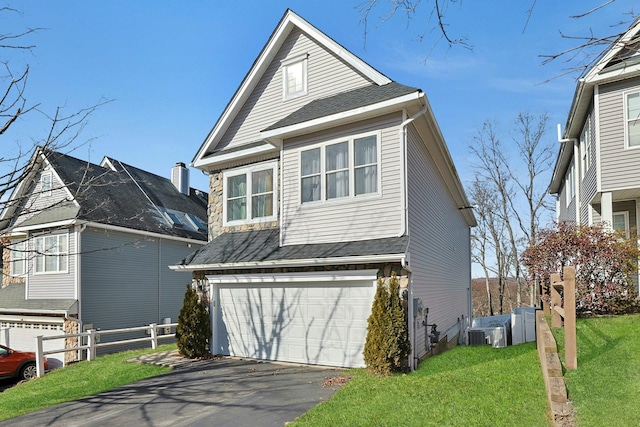 view of front of property with central air condition unit, an attached garage, a front yard, and fence