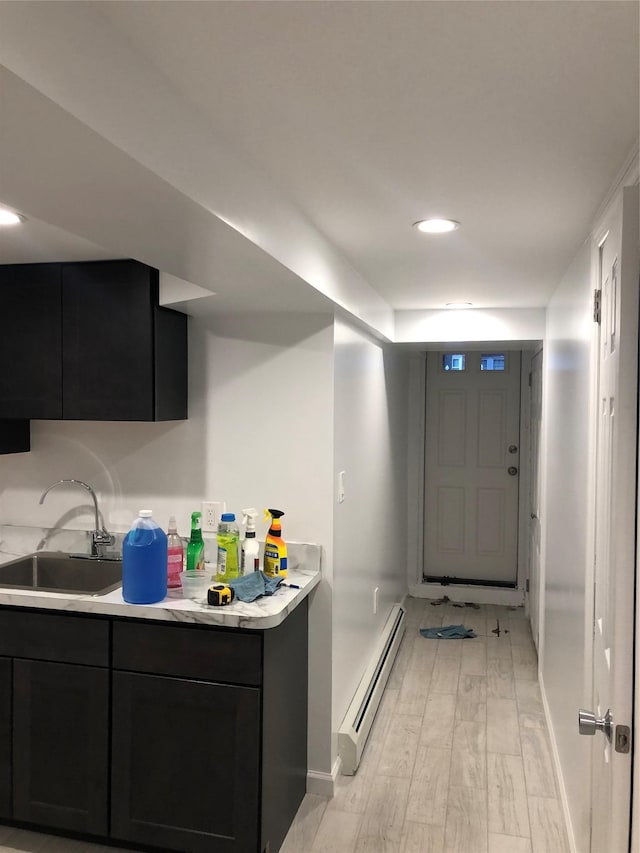 kitchen featuring a baseboard radiator, sink, and light hardwood / wood-style flooring