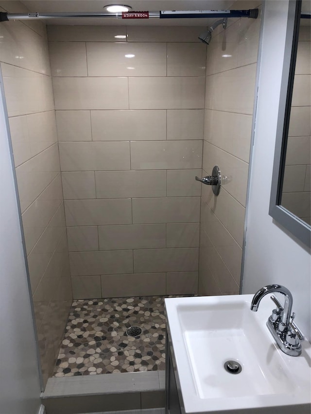 bathroom featuring a tile shower and sink