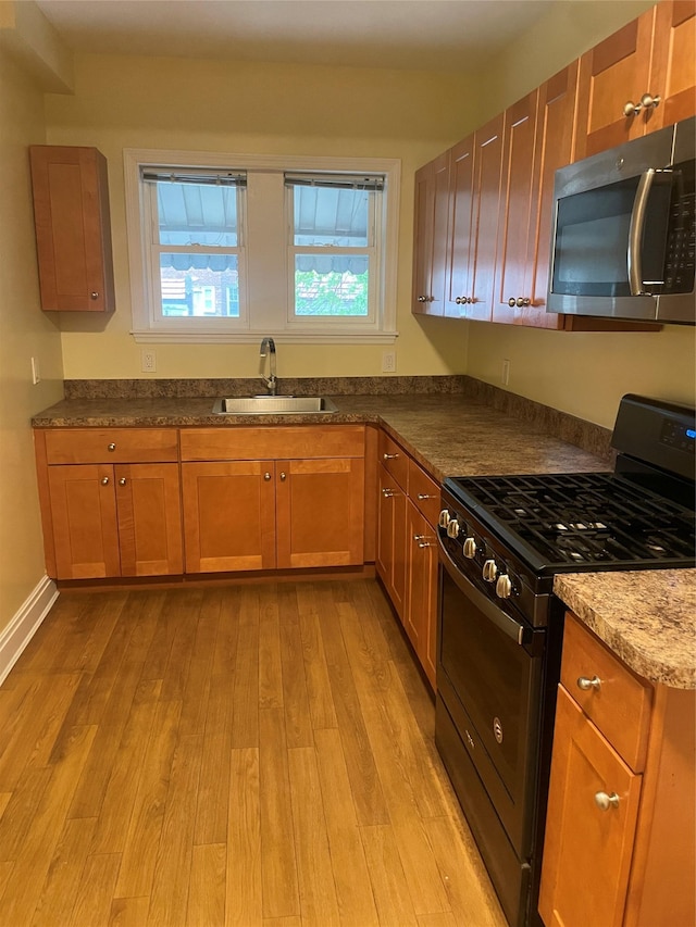 64-18 84th Pl, Middle Village, NY 11379 - kitchen with black range with gas stovetop, stainless steel microwave, a sink, light wood finished floors, and dark stone countertops