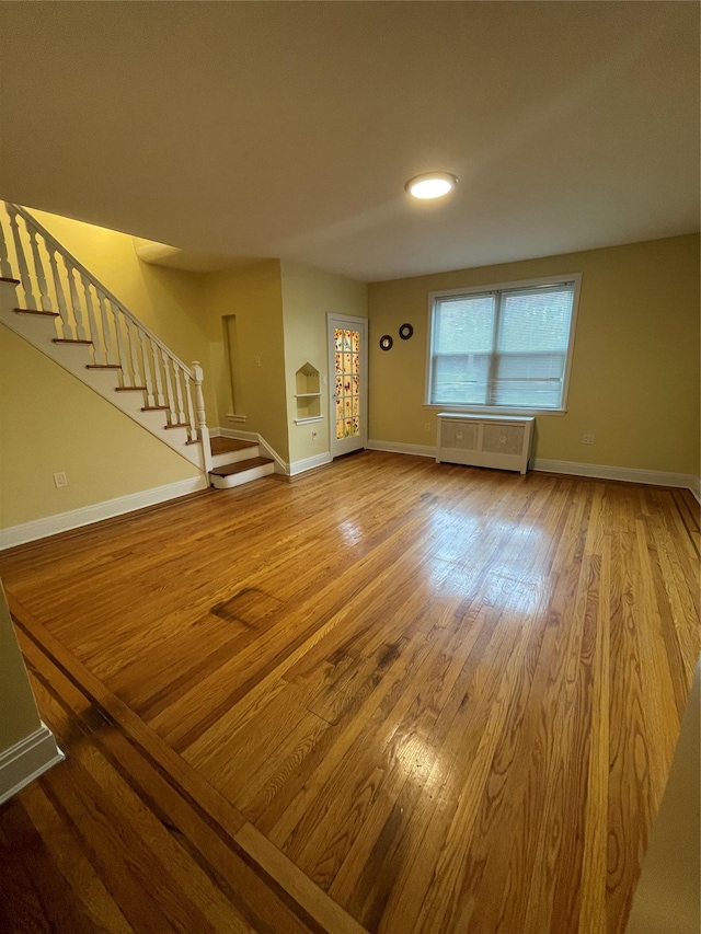 64-18 84th Pl, Middle Village, NY 11379 - unfurnished living room with stairs, wood finished floors, and baseboards