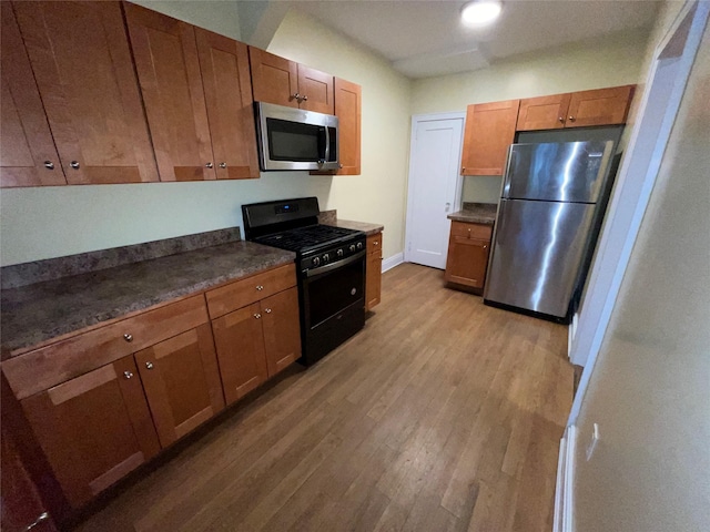 64-18 84th Pl, Middle Village, NY 11379 - kitchen with stainless steel appliances, dark countertops, light wood-type flooring, and brown cabinets