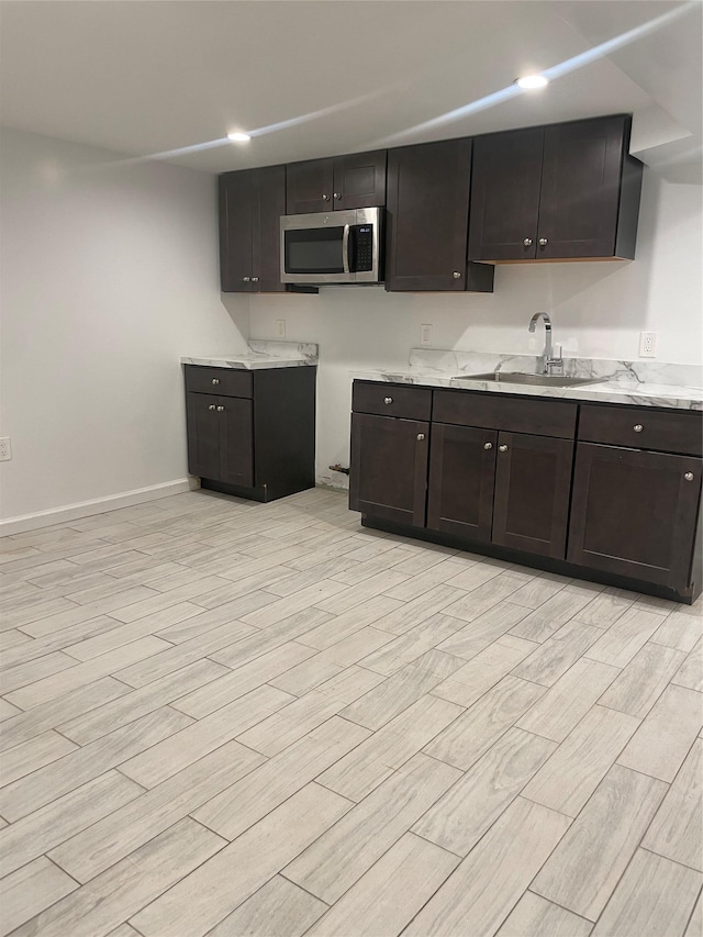 64-18 84th Pl, Middle Village, NY 11379 - kitchen with stainless steel microwave, a sink, light wood finished floors, dark brown cabinets, and baseboards