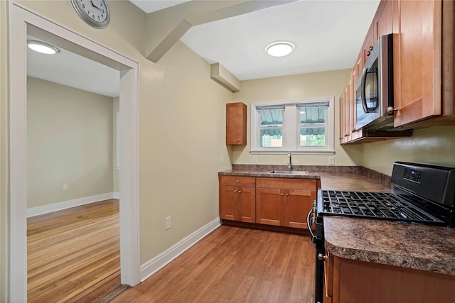 64-18 84th Pl, Middle Village, NY 11379 - kitchen featuring gas stove, stainless steel microwave, dark countertops, light wood-style floors, and brown cabinetry