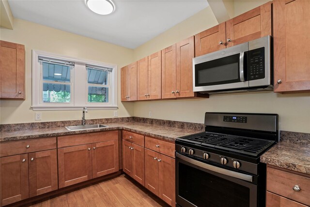 64-18 84th Pl, Middle Village, NY 11379 - kitchen featuring appliances with stainless steel finishes, dark countertops, light wood-style floors, and brown cabinets