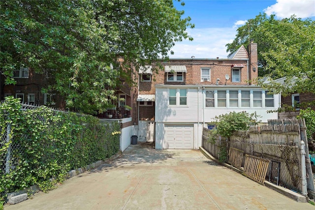 64-18 84th Pl, Middle Village, NY 11379 - back of property with a garage, driveway, a chimney, and brick siding