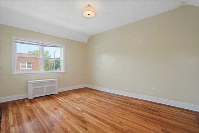 64-18 84th Pl, Middle Village, NY 11379 - unfurnished room featuring radiator heating unit, lofted ceiling, a smoke detector, and light wood finished floors