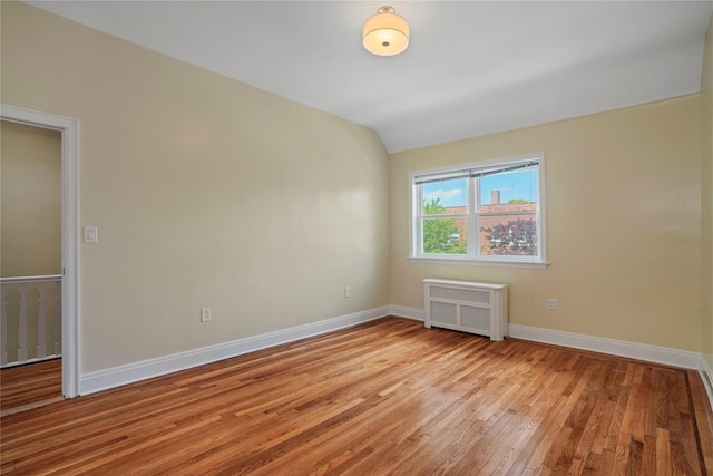 64-18 84th Pl, Middle Village, NY 11379 - spare room with radiator heating unit, light wood-style floors, and lofted ceiling