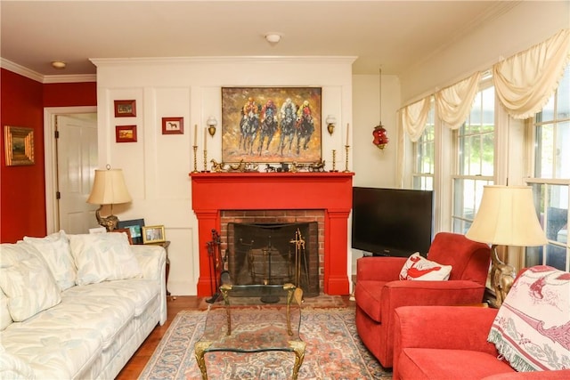 living room with a brick fireplace, hardwood / wood-style flooring, and ornamental molding