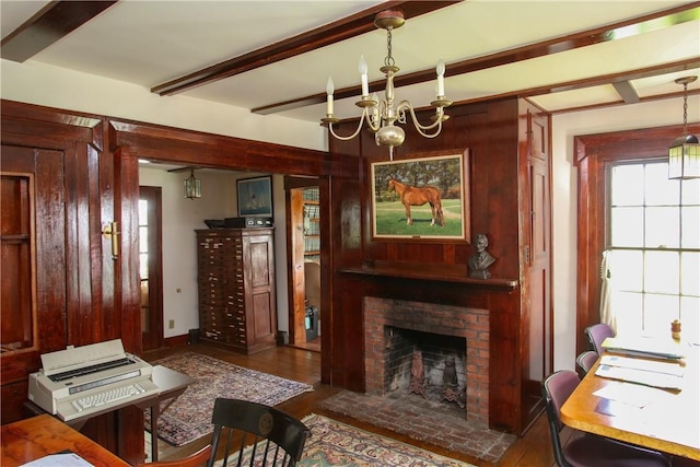 living room with beamed ceiling, a brick fireplace, dark hardwood / wood-style floors, and a chandelier