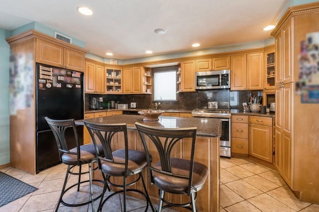 kitchen featuring tasteful backsplash, light tile patterned floors, stainless steel appliances, and a center island