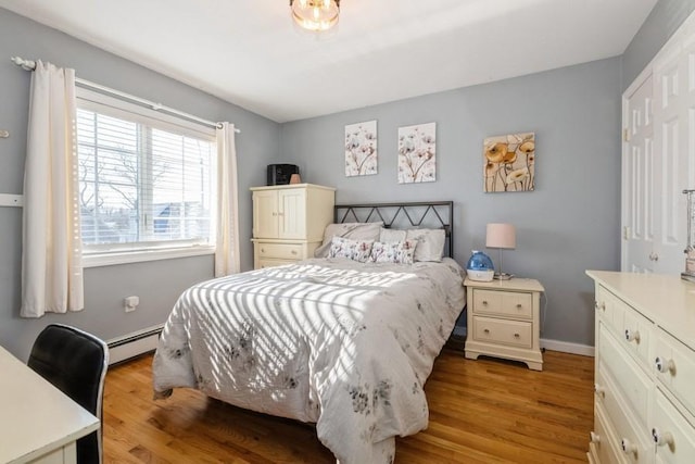 bedroom featuring a baseboard heating unit and light hardwood / wood-style floors