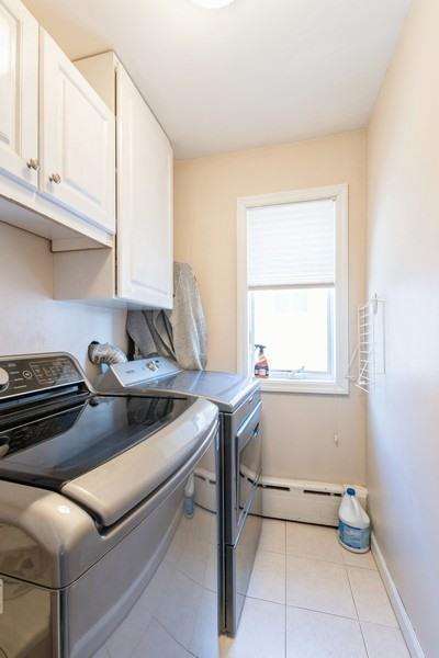 washroom with cabinets, separate washer and dryer, light tile patterned floors, and baseboard heating