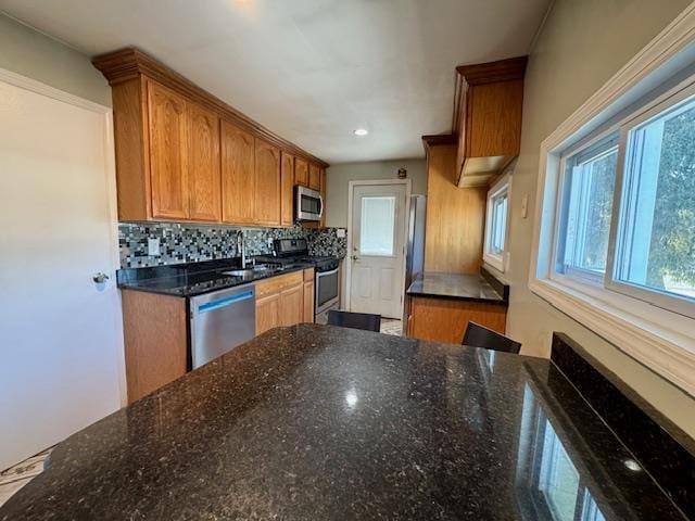 kitchen featuring stainless steel appliances, tasteful backsplash, sink, and dark stone countertops