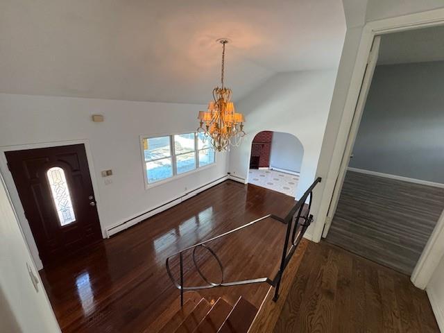 foyer entrance featuring a notable chandelier, vaulted ceiling, dark hardwood / wood-style floors, and a baseboard heating unit