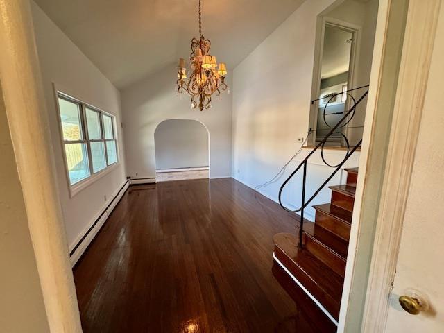 unfurnished dining area featuring vaulted ceiling, dark hardwood / wood-style floors, an inviting chandelier, and baseboard heating