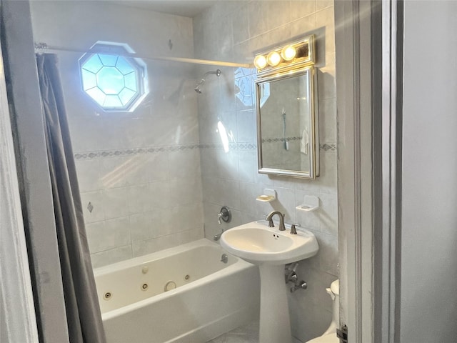 bathroom with tile walls, tiled shower / bath combo, and toilet