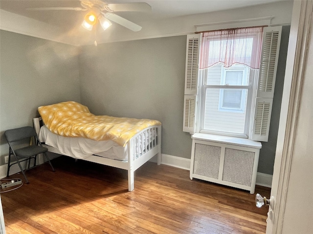 bedroom featuring hardwood / wood-style floors, radiator heating unit, and ceiling fan