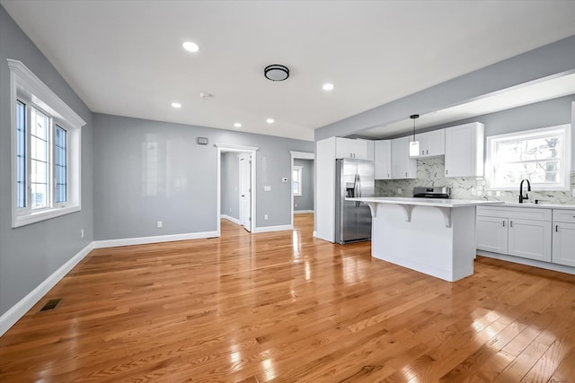 kitchen with white cabinetry, hanging light fixtures, stainless steel appliances, and a kitchen breakfast bar