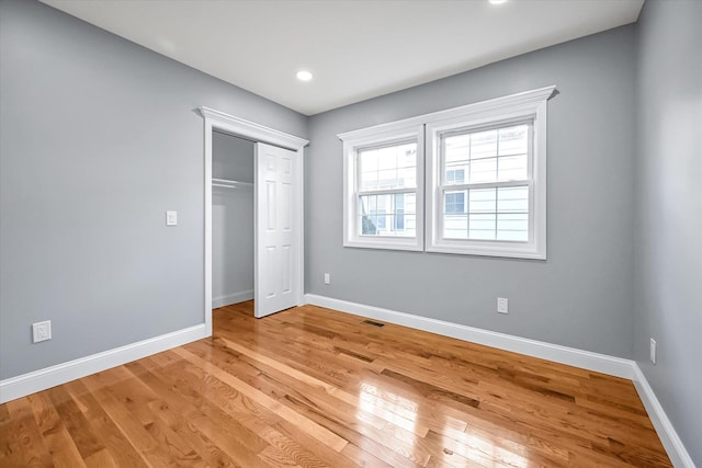 unfurnished bedroom with light wood-type flooring and a closet