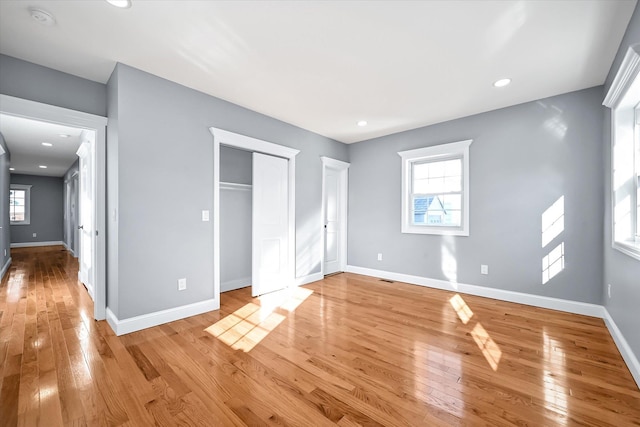 unfurnished bedroom featuring multiple windows and light hardwood / wood-style floors