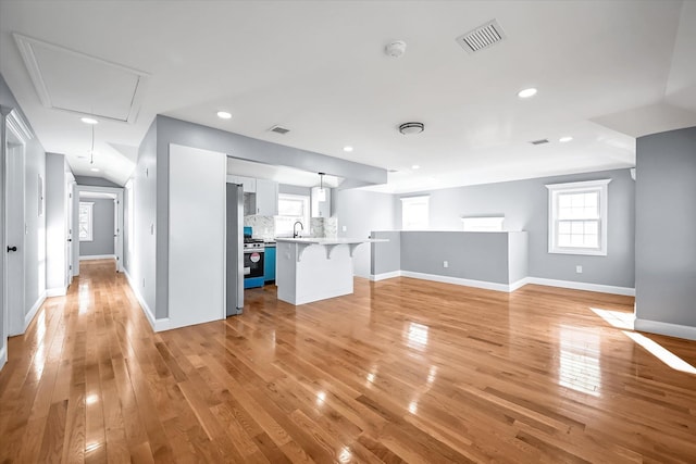 unfurnished living room with sink and light hardwood / wood-style flooring