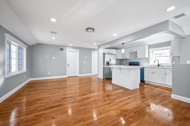 kitchen featuring pendant lighting, a kitchen breakfast bar, a center island, white cabinets, and decorative backsplash