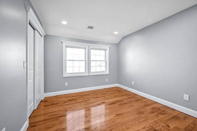 unfurnished bedroom with lofted ceiling, light hardwood / wood-style flooring, and a closet