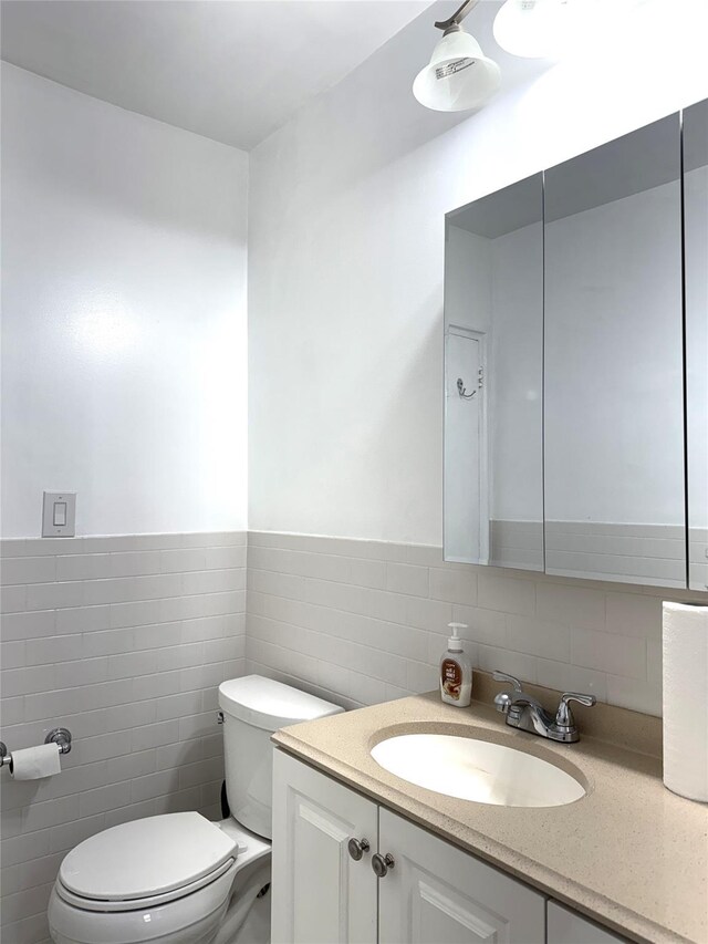 143-50 Hoover Ave Unit 204, Briarwood, NY 11435 - bathroom featuring tile walls, a wainscoted wall, toilet, and vanity